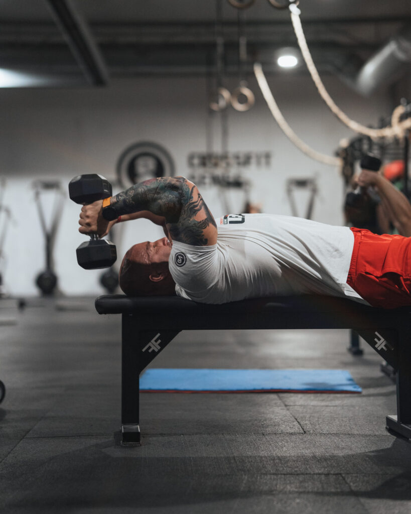 Člen CrossFit Senec robí tlak s jednoručkami na lavičke